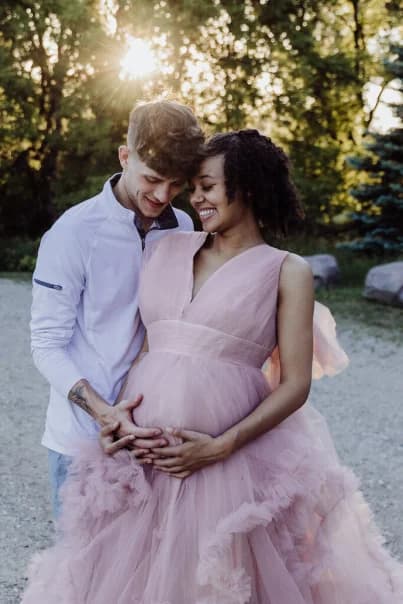 A couple at a maternity session photographed outdoors at golden hour.